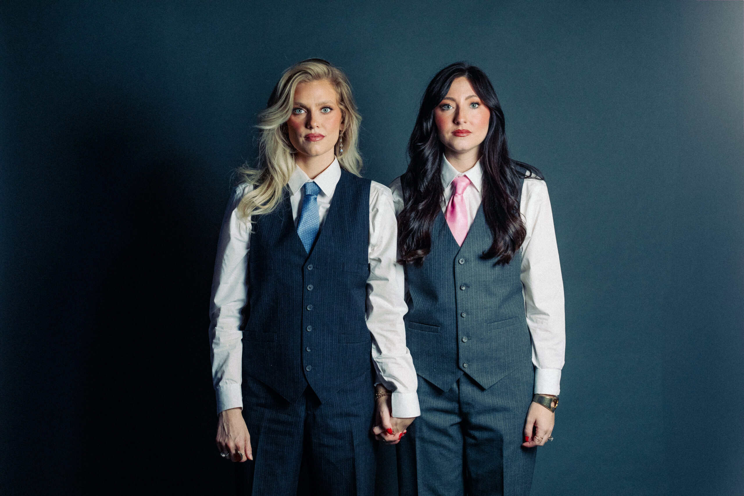 Sara Chambers and Hannah Istvanko, co-owners of Privy Clear, standing in suits with blue and pink ties